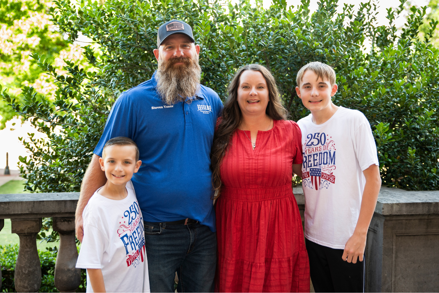 Steven and Jessica Yones stand with their two sons in an outdoor setting posing for a family picture.